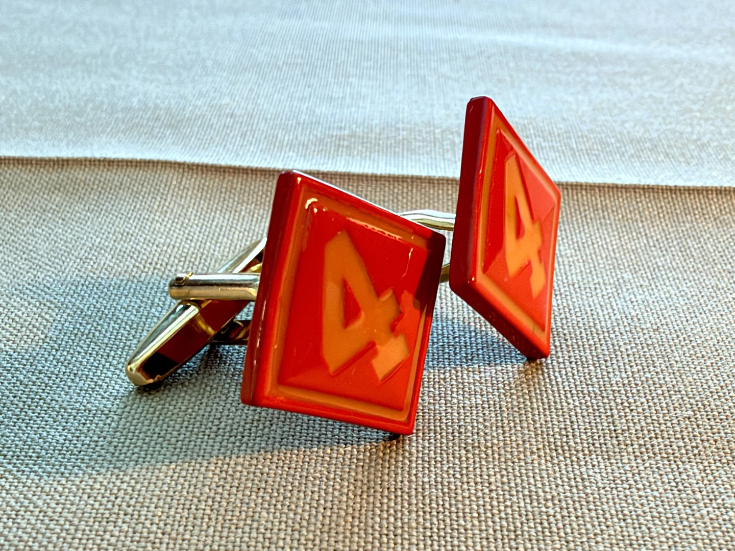 Side angle of actual 4th Marine Division cufflinks showing the red faces and fastening hardware on khaki fabric